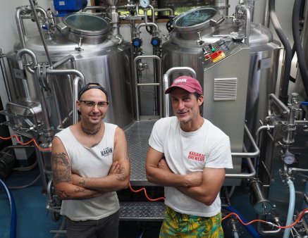 Brewers Mehdy and Philippe standing in front of their tanks in the kura